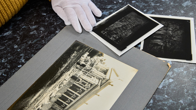 Photograph print and negatives on table with gloved hand pointing