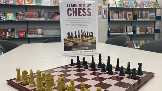 Chess board with Chess Club poster in the background